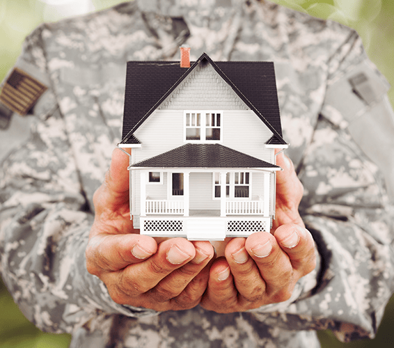 Person in a military uniform holding a model house